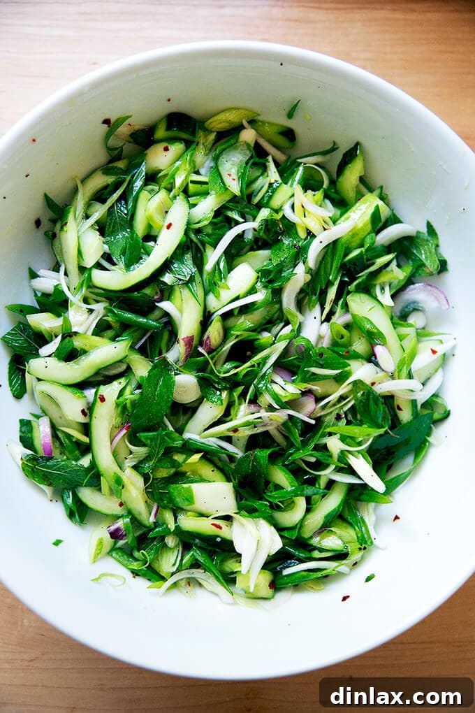 A refreshing cucumber and mint salad in a stylish white bowl, ready to be served.