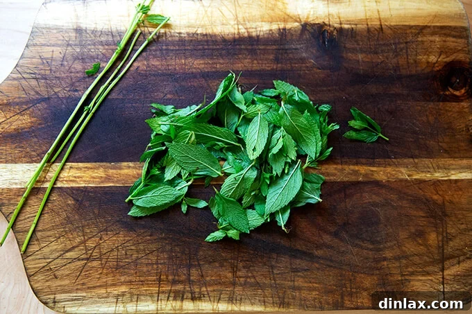 Fresh mint leaves, vibrant green, resting on a wooden board, ready to be added to the salad.