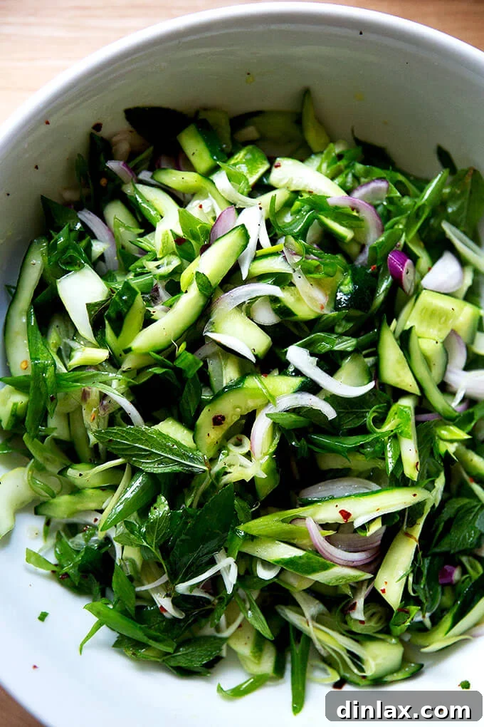 A vibrant cucumber salad, fully tossed and ready to be served in a large white bowl.