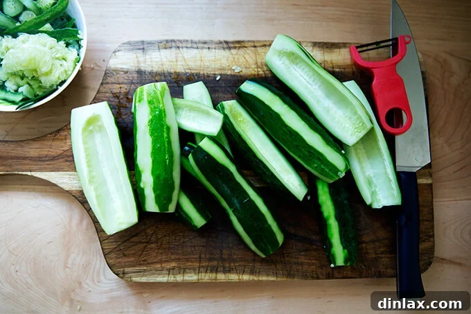 Peeled cucumbers with striped skin resting on a wooden cutting board, showcasing the zebra-style peeling technique.