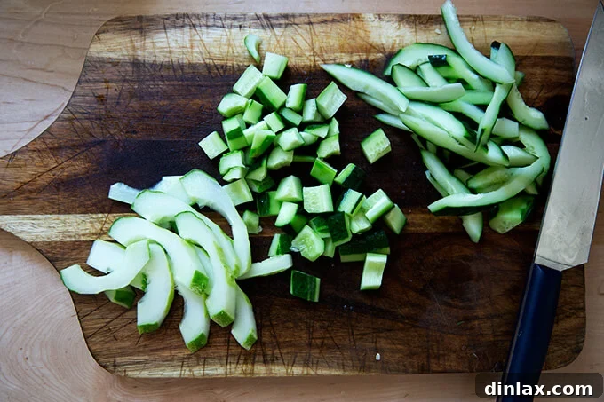 Evenly sliced cucumbers arranged on a cutting board, prepared for the next step in the salad recipe.