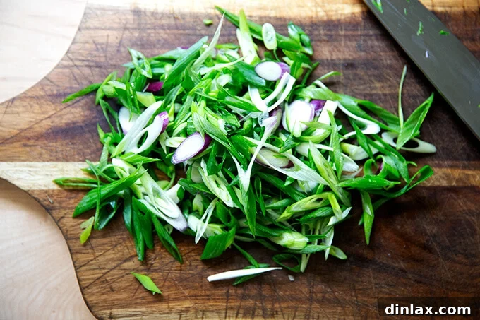 Thinly sliced scallions arranged on a cutting board, ready for the next stage of preparation.