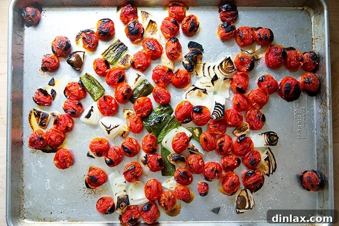 Effortless Homemade Red Enchilada Sauce 5 A sheet pan filled with perfectly broiled vegetables – tomatoes, onions, garlic, and jalapeño – showing visible charring and blistering, ready for the next step.