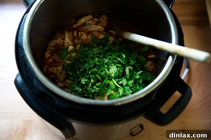 Smoky Instant Pot Chicken Tinga 12 An instant pot holding chicken tinga with cilantro added.