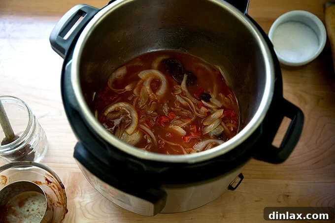 Smoky Instant Pot Chicken Tinga 7 An Instant pot holding water, tomatoes, onions, and chipotle in adobo sauce.