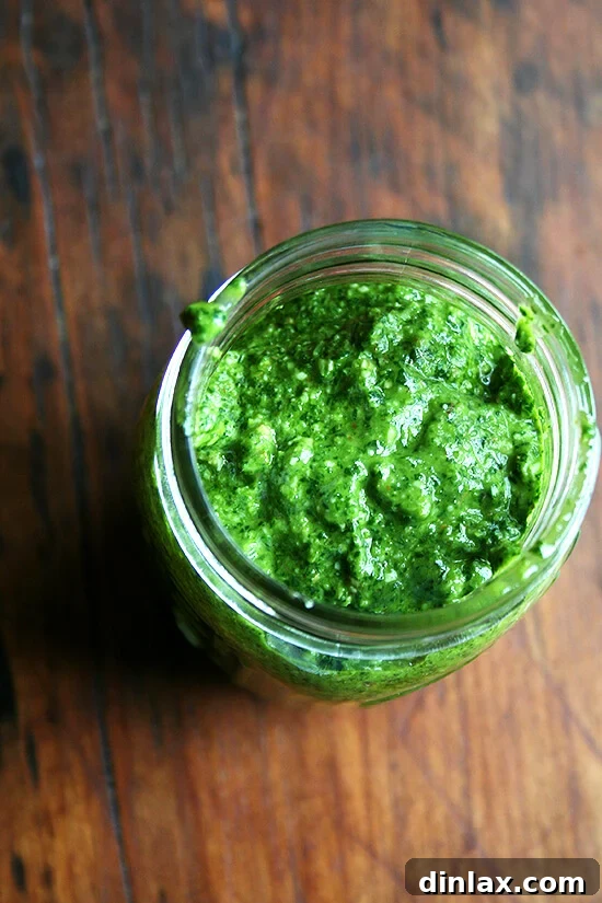 A jar of freshly made, vibrant green homemade pesto sauce, ready for use in pasta or other dishes, showcasing its delicious texture and color.