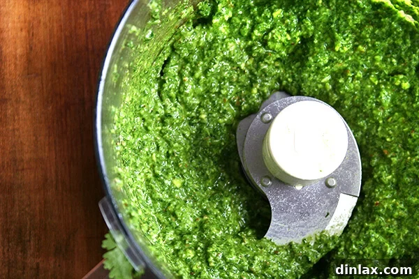 Pesto sauce fully puréed and ready in a food processor, showcasing its smooth, vibrant green texture.