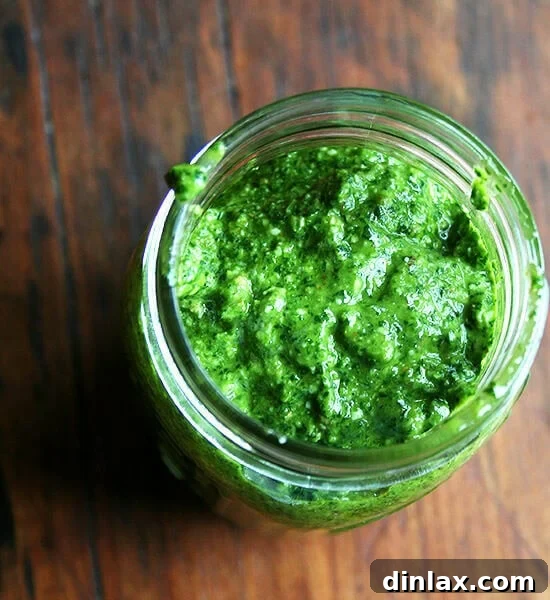 A jar of homemade pesto sauce, perfect for serving with pasta or as a versatile condiment, topped with a layer of olive oil to preserve freshness.