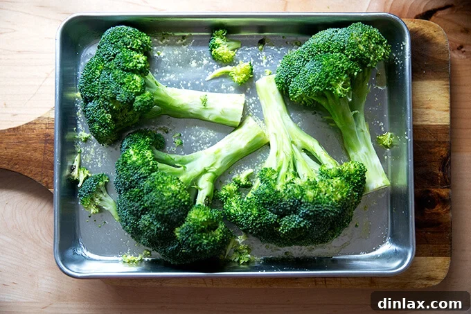 Two halved heads of broccoli on a sheet pan.