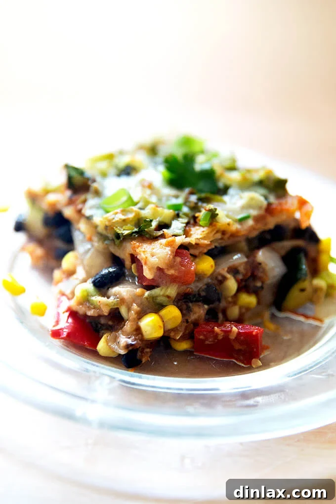 Southwestern Veggie Tortilla Stack 11 A single, perfectly cut piece of vegetarian tortilla casserole, showcasing its distinct layers of tortilla, vegetables, beans, and melted cheese, served hot and ready to eat.