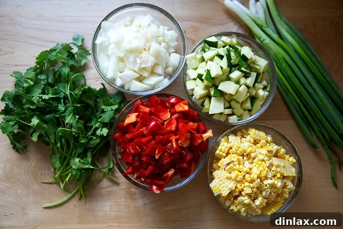 Southwestern Veggie Tortilla Stack 3 A flat lay photograph showcasing all the fresh, colorful ingredients neatly arranged on a countertop, ready to be prepared for the sautéed summer vegetable tortilla casserole. Ingredients include bell peppers, zucchini, corn, onions, black beans, tortillas, herbs, and cheese.