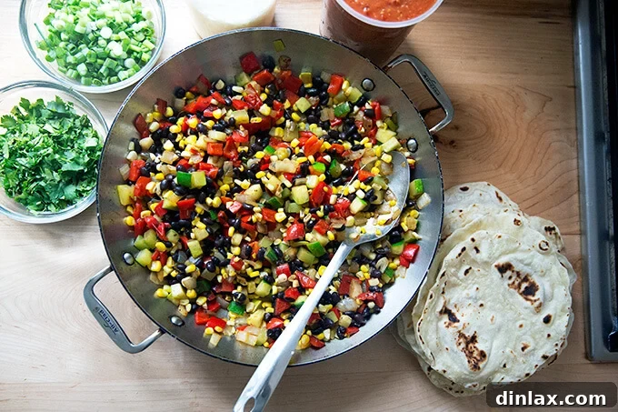 Southwestern Veggie Tortilla Stack 5 A countertop view of a skillet containing a hearty mixture of sautéed summer vegetables and black beans, stirred together and seasoned, ready to be layered into the enchilada casserole.