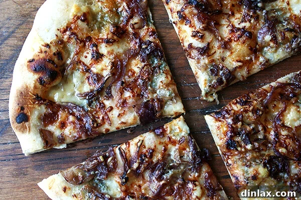 A gourmet fig jam, caramelized onions, and blue cheese pizza, sliced and ready to serve.