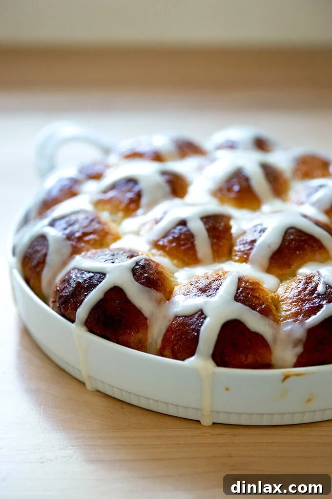 A freshly baked pan of golden brown hot cross buns with white icing crosses.