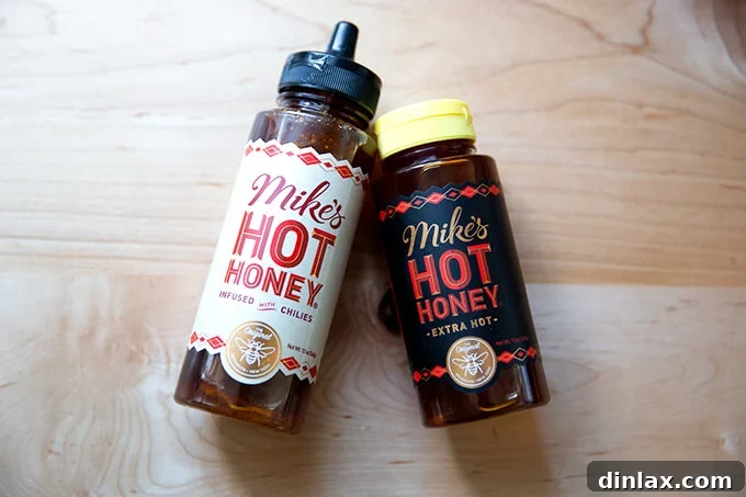 The 2021 Holiday Gift Edit 19 Two bottles of Mike's Hot Honey, a popular sweet and spicy condiment, on a kitchen surface.