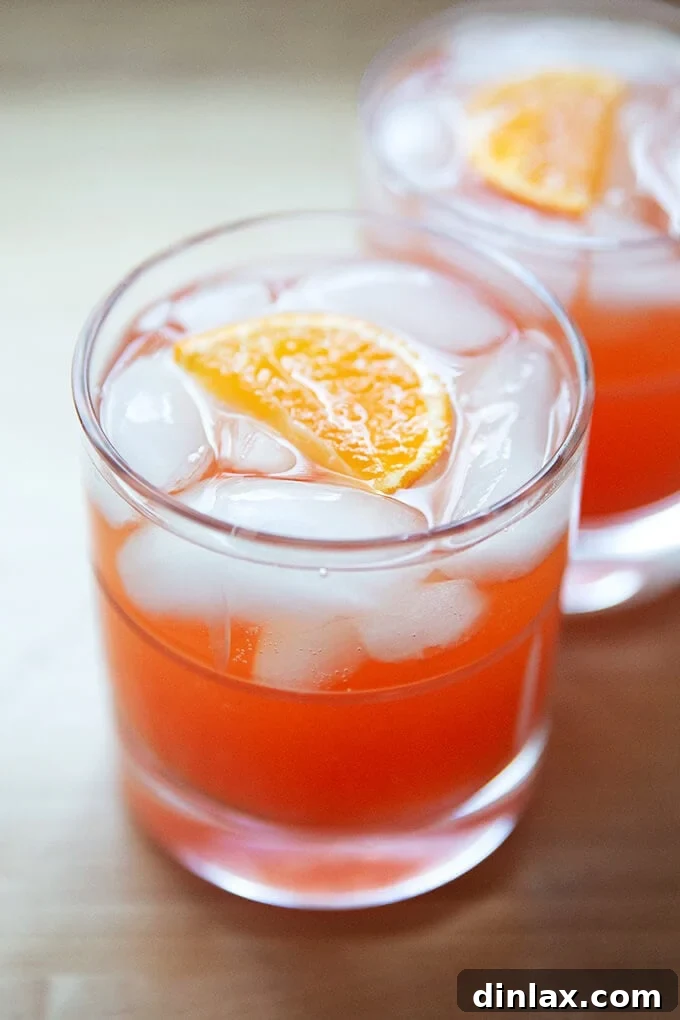 Two glasses of a vibrant Tangerine Spritz, garnished with citrus slices, ready to be enjoyed.