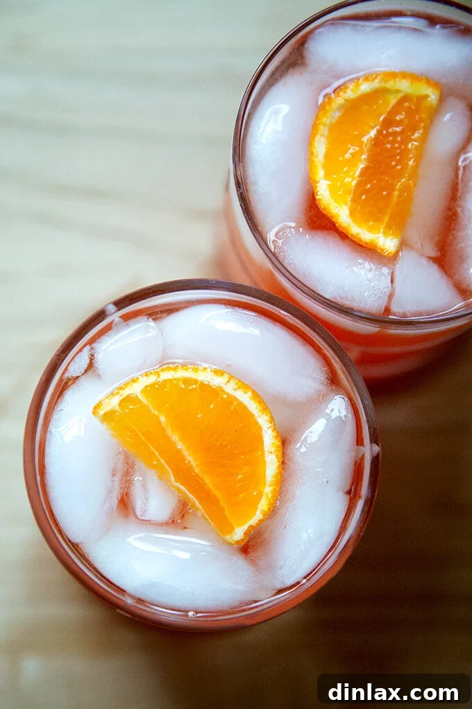 An overhead view of two beautifully garnished Tangerine Spritzes, with orange slices, ready to be served.