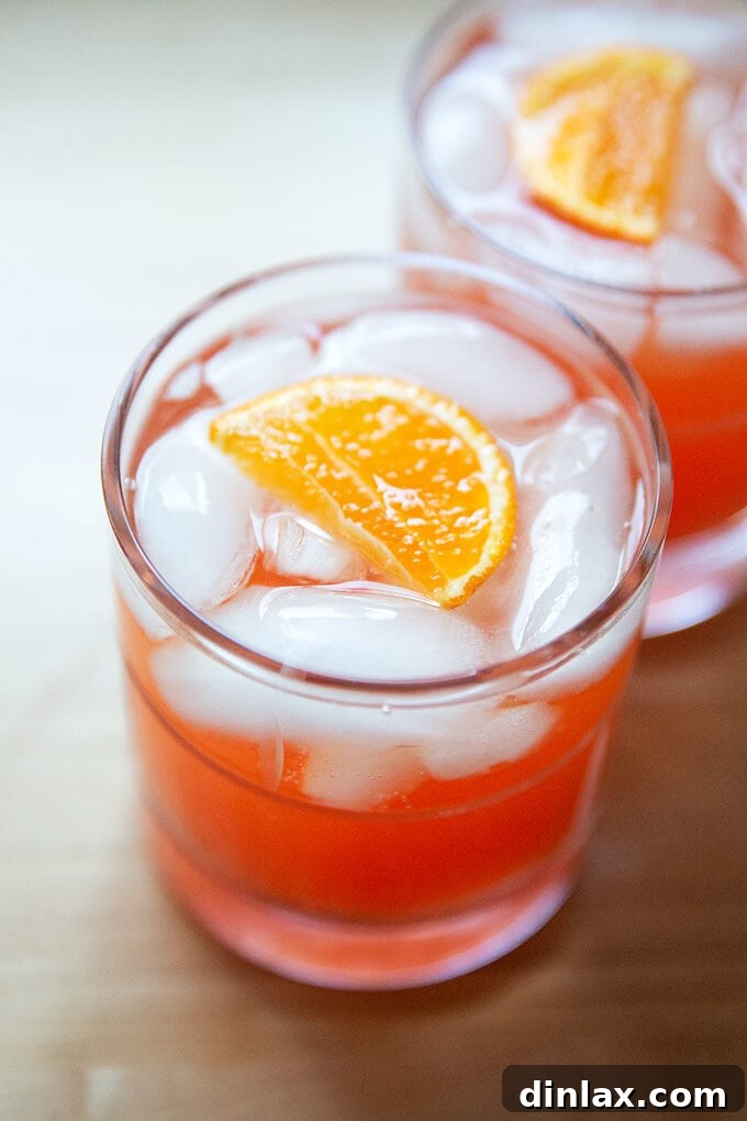 Two enticing glasses of a Tangerine Spritz, perfectly mixed and garnished, set against a warm background.