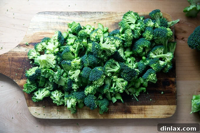 Finely chopped broccoli florets and tender stems on a cutting board, prepared for the salad.