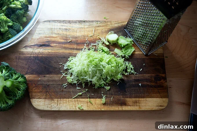Close-up of finely grated broccoli stem on a cutting board, ready to be incorporated into the salad.