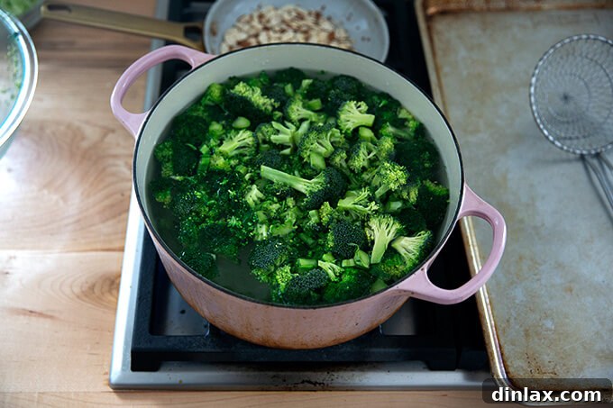 A large pot of vigorously boiling water, with vibrant green broccoli florets being blanched.