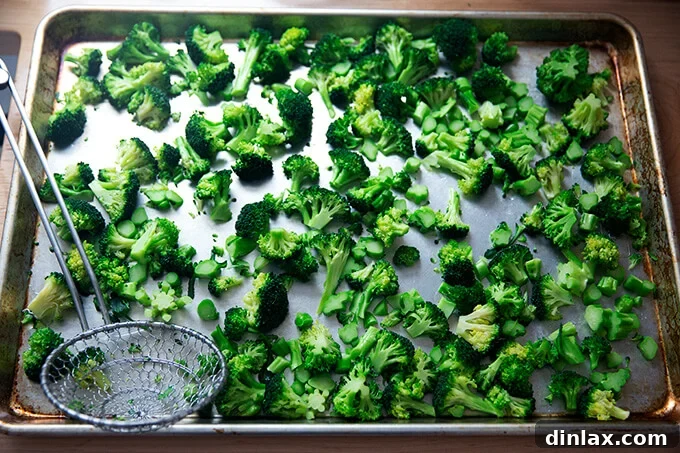 Bright green blanched broccoli cooling on a sheet pan, steam gently rising.
