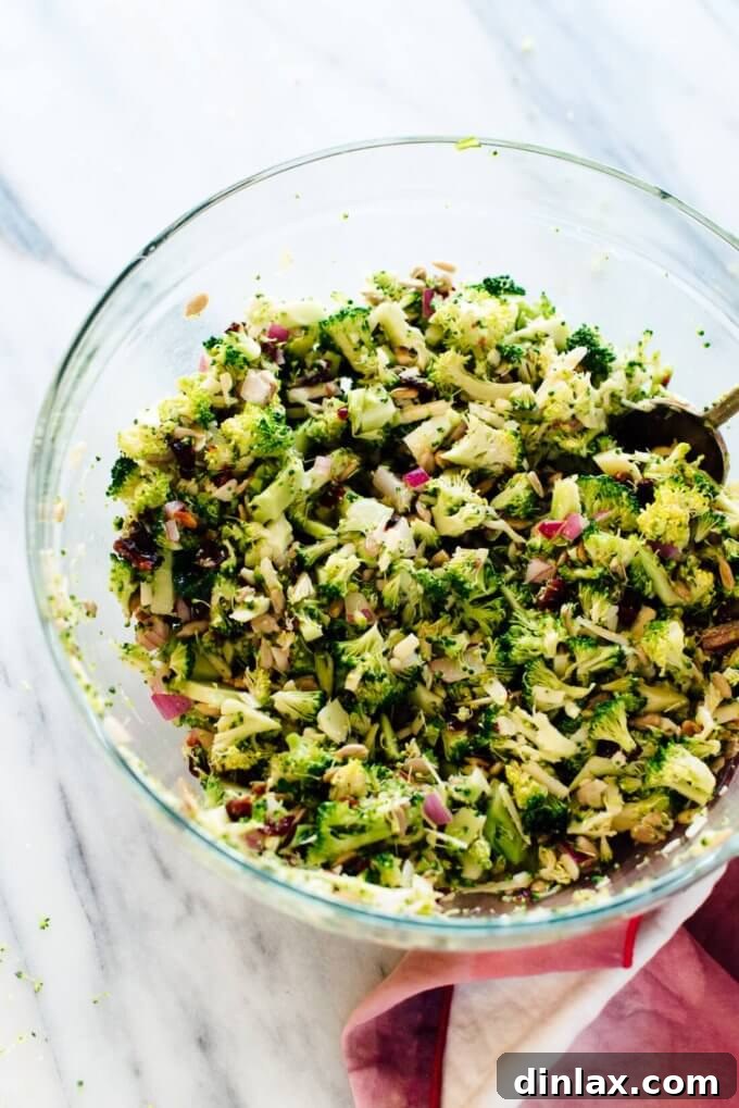 A large serving bowl filled with Cookie and Kate's signature broccoli salad, mixed with sunflower seeds, dried cranberries, and cheddar cheese.
