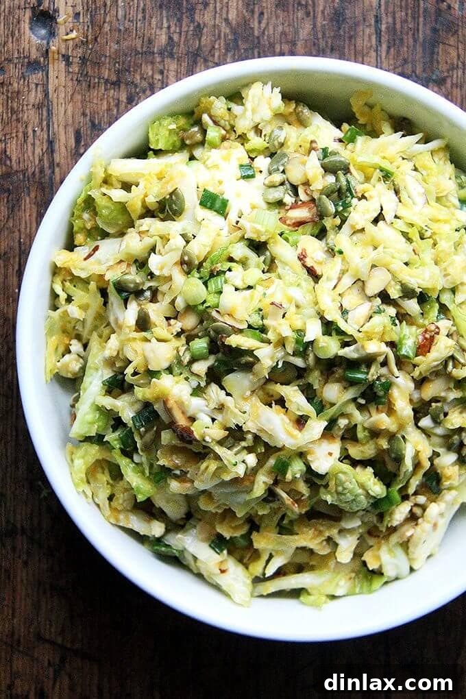 A colorful bowl of cabbage slaw generously topped with a rich miso-carrot dressing, alongside toasted almonds and pumpkin seeds.