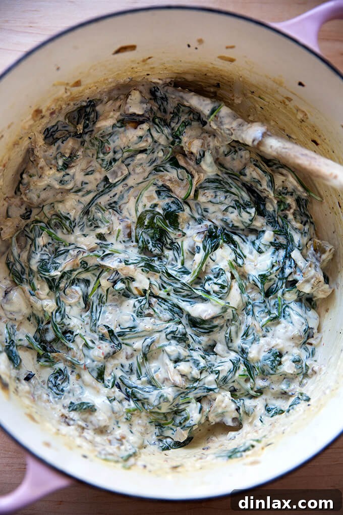 A large pot filled with a finished batch of creamy spinach artichoke dip, ready to be served.
