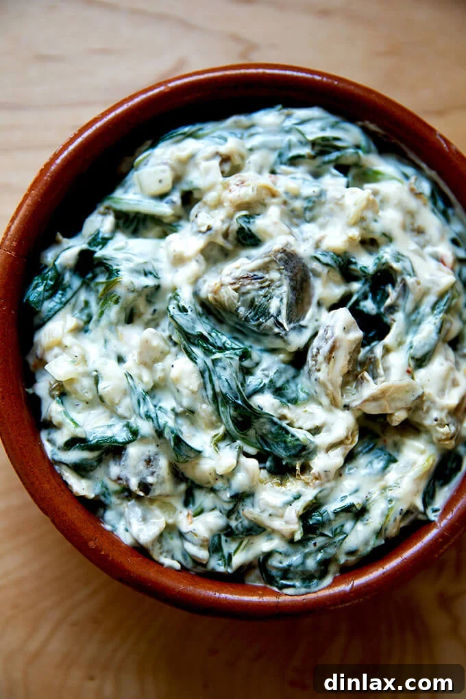 A small, oven-safe dish filled with spinach-artichoke dip, prepped for broiling.