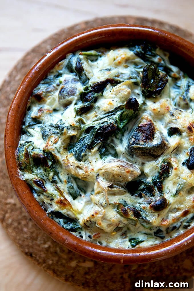 A small dish of spinach-artichoke dip, freshly broiled with a golden, bubbly crust.