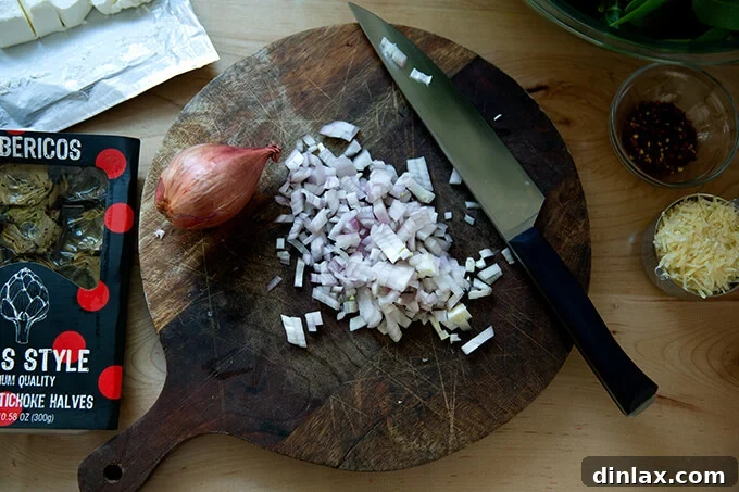 Finely diced shallots on a cutting board, prepared for sautéing.