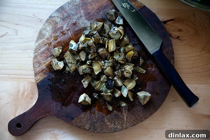 Coarsely chopped, drained artichoke hearts on a cutting board.