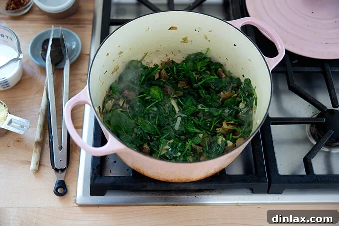 A pot of wilted spinach and artichoke hearts, combined and cooked down.
