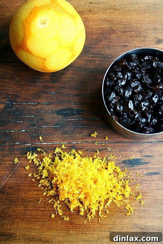 Fresh orange zest and simmered raisins ready for the bran muffin batter An orange with its zest grated and a bowl of simmered raisins, key ingredients for the bran muffins.
