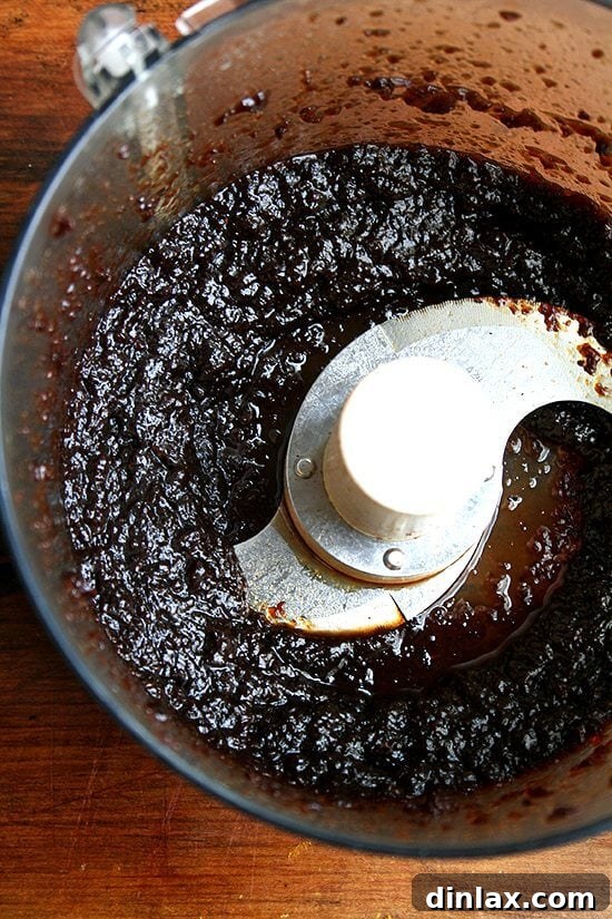 Puréeing simmered raisins for enhanced flavor and texture A food processor blending simmered raisins into a smooth purée for the muffin batter.