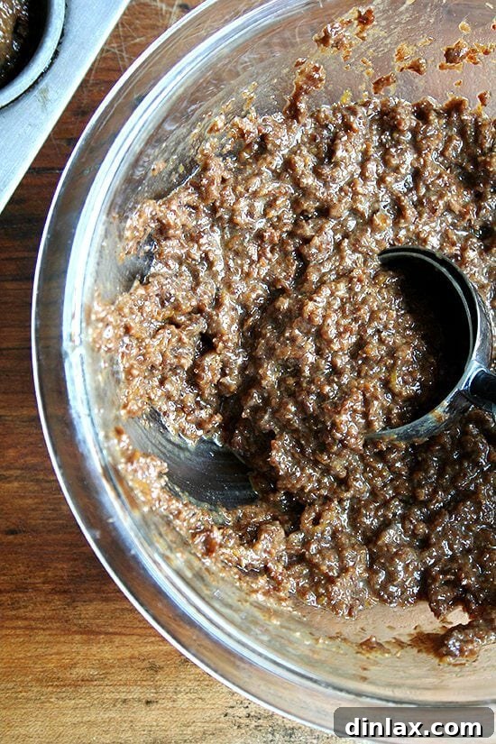 Preparing individual bran muffins for baking A close-up shot of bran muffin batter being scooped, highlighting its texture.