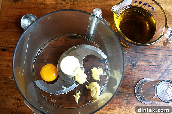 Ingredients for homemade mayonnaise laid out: egg yolk, Dijon mustard, salt, pepper, lemon juice, and neutral oil.