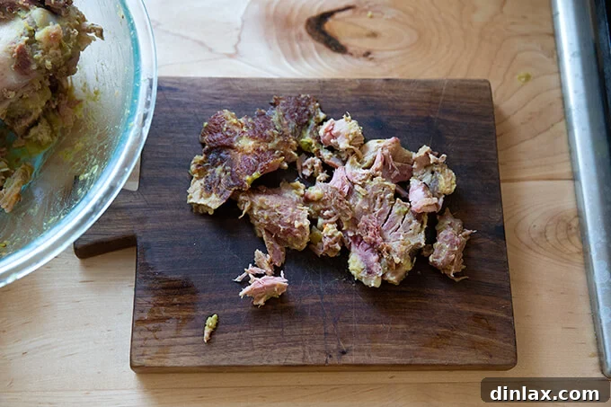 Tender, savory ham pieces expertly chopped on a cutting board, prepared to be reintroduced into the comforting split pea soup.