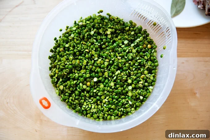 A colander filled with perfectly rinsed green split peas, glistening and ready to be added to the simmering soup pot.