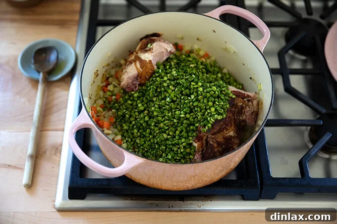 A large pot showing a harmonious blend of tender vegetables, a rich ham bone, and vibrant green split peas, setting the stage for a flavorful soup.