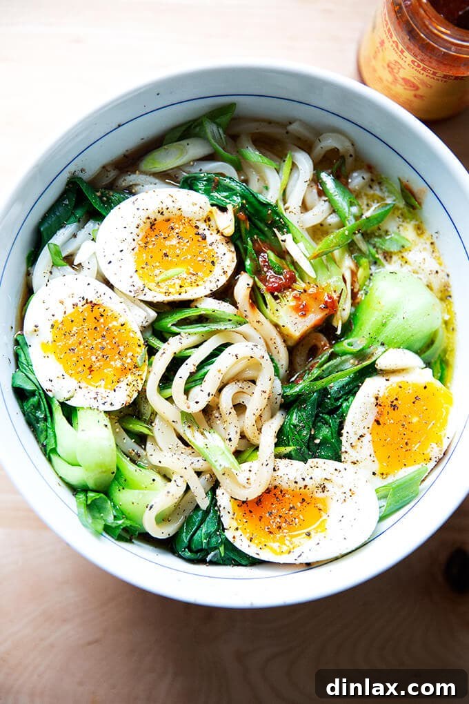 Udon: A Culinary Revelation 14 A steaming bowl of udon noodles, beautifully arranged with soft-boiled eggs and a hint of chili sauce, capturing the comforting essence of a perfect meal.