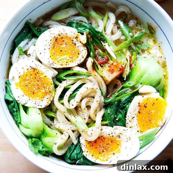 A bowl of udon noodles topped with eggs and hot sauce.