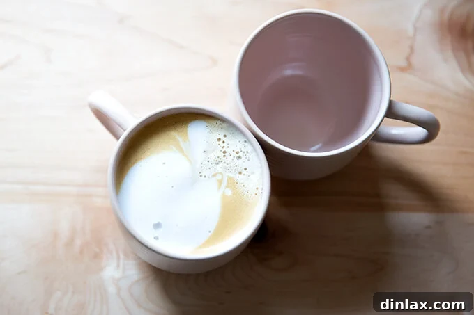 An overhead shot of two pink mugs, one holding a delicious homemade latte.