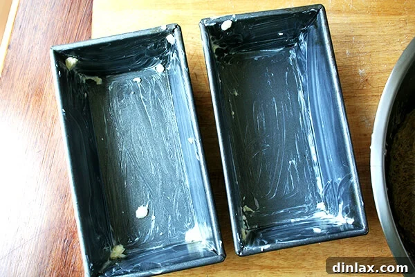 Generously buttered loaf pans, prepared for the oatmeal bread dough.