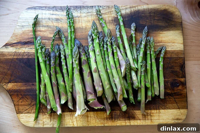 Freshly gathered asparagus spears ready for preparation, laid out neatly on a wooden cutting board.