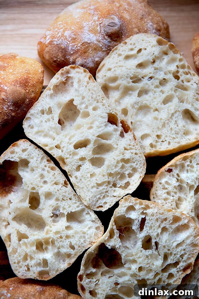 A generous pile of halved ciabatta rolls, showcasing their fluffy, open crumb.