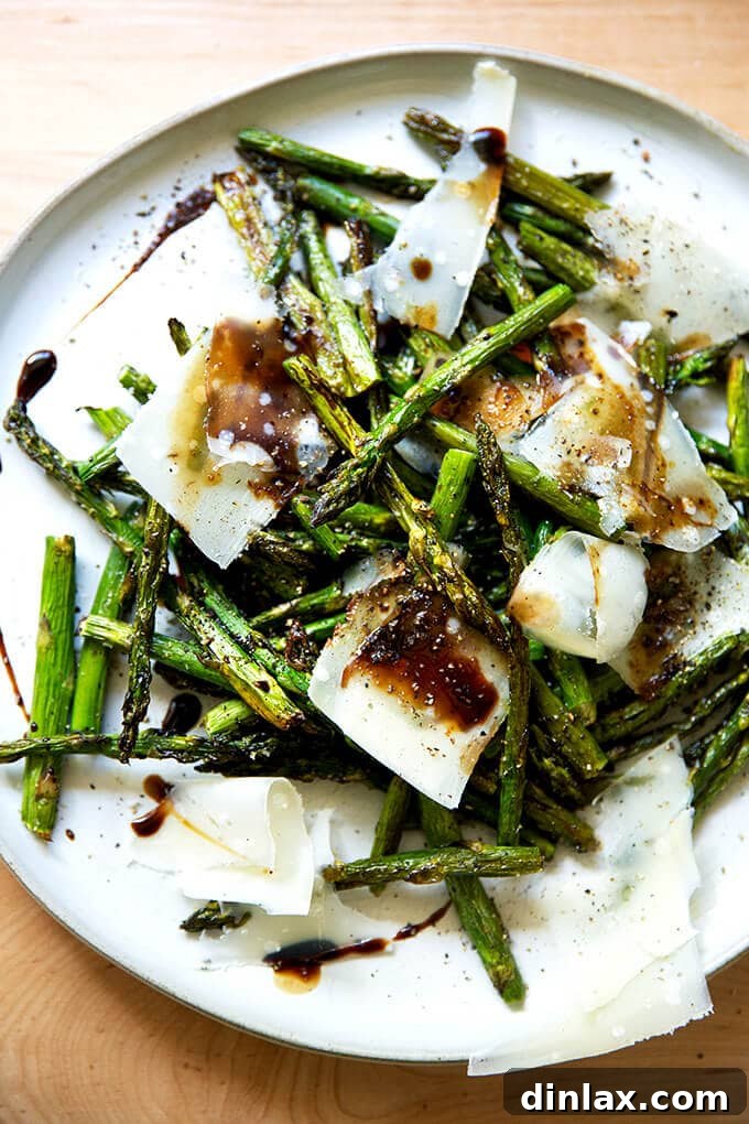 Effortless Balsamic Parmesan Roasted Asparagus 2 Perfectly roasted asparagus spears garnished with shaved Parmesan cheese and a drizzle of rich balsamic glaze, served on a white plate, ready to enjoy.