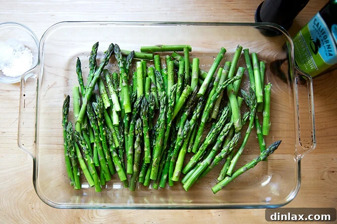 Effortless Balsamic Parmesan Roasted Asparagus 5 Raw asparagus spears, cut in half, arranged neatly in a 9x13-inch glass baking dish, ready to be seasoned and roasted.