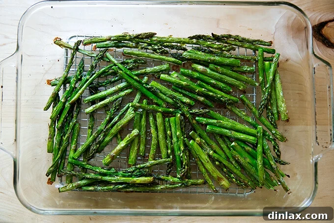 Effortless Balsamic Parmesan Roasted Asparagus 7 Roasted asparagus spears, golden brown with slightly charred tips, resting in a 9x13-inch glass baking dish fresh out of the oven.